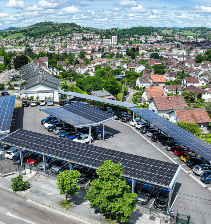 lors d'une journ&eacute;e ensoleill&eacute;e, photo drone vue du ciel du parking en ombri&egrave;re du SIDEC du Jura avec vue panoramique sur la ville de Lons-le-Saunier