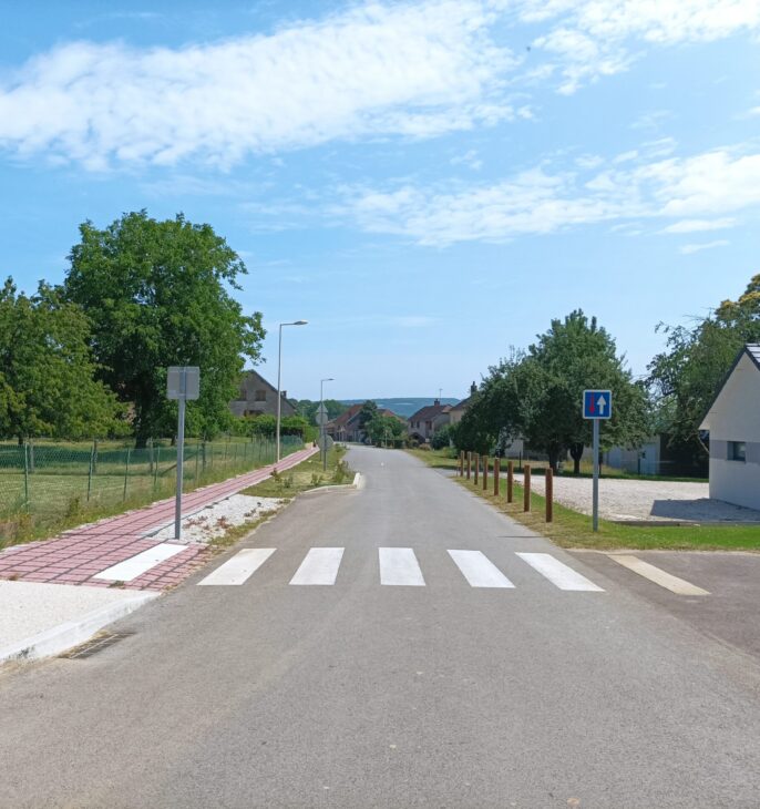 Rue r&eacute;am&eacute;nag&eacute;e avec trottoir s&eacute;curis&eacute;, passage pi&eacute;ton et espaces publics dans un quartier r&eacute;sidentiel.