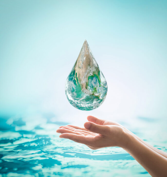 Grosse goute d'eau dans laquelle on vit la terre en l&eacute;vitation au dessus d'une main