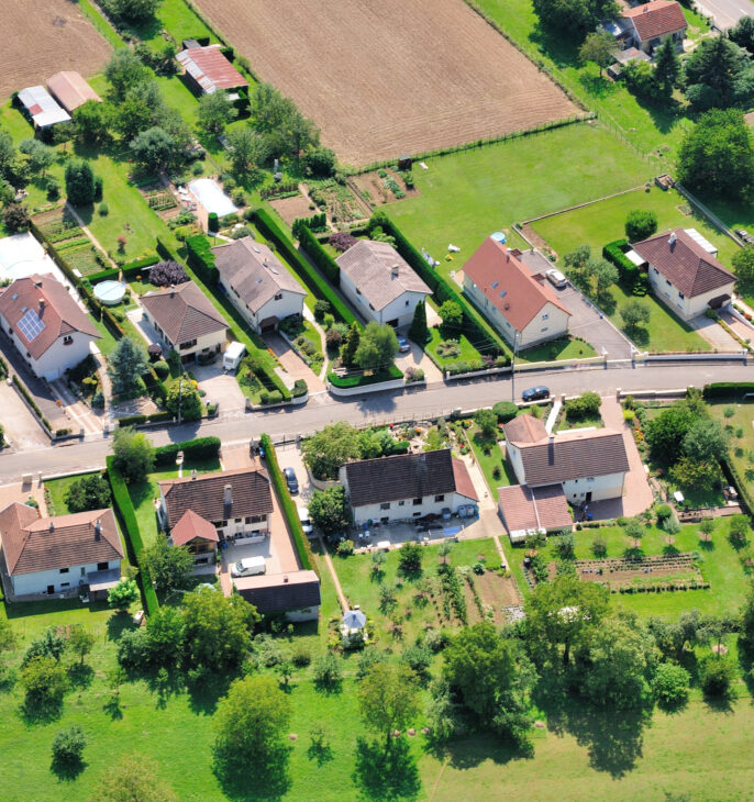 Vue a&eacute;rienne d'un quartier r&eacute;sidentiel avec habitations individuelles, jardins et espaces verts.
