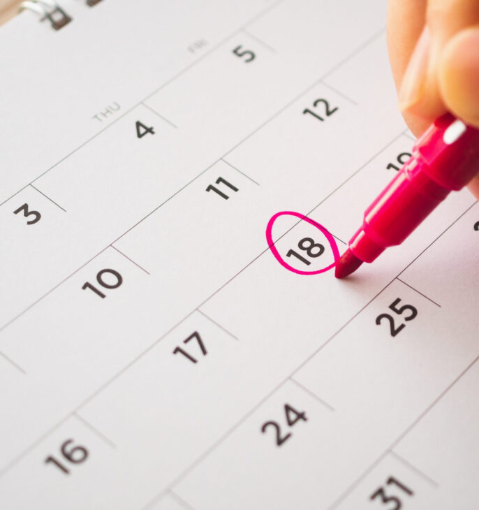 calendrier mensuel avec un main qui entoure un rouge une date