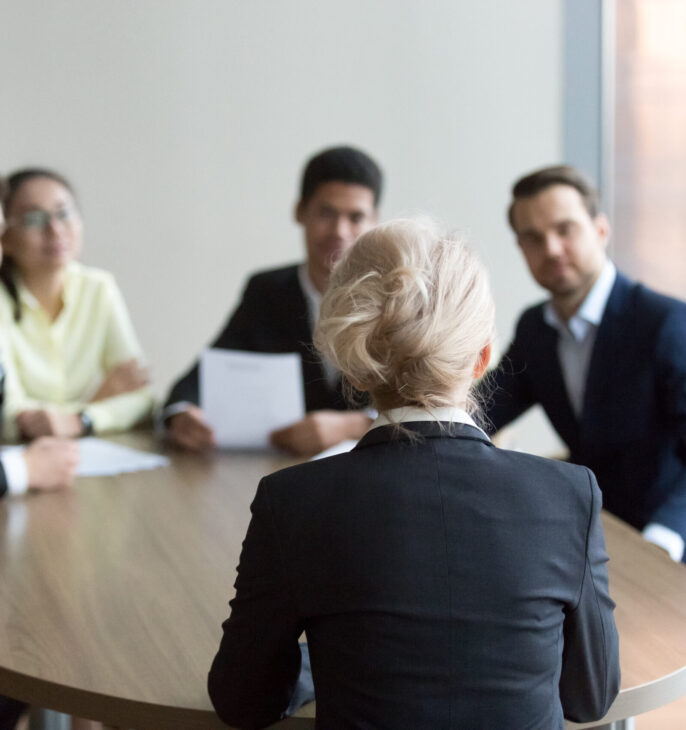 Table de r&eacute;union ovale avec cartes personnes autour dont une femme au bout de la table